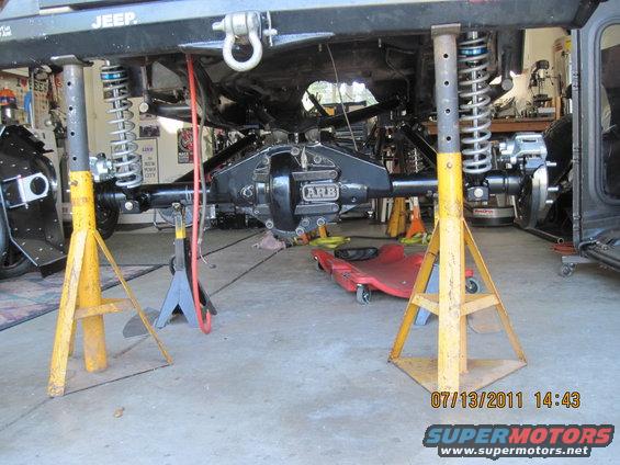 Jeep frame on jack stands, showing rear axle with ARB differential cover and suspension components