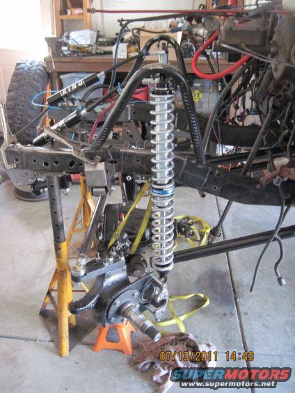 Jeep CJ frame with King shocks and suspension parts, supported by jack stands