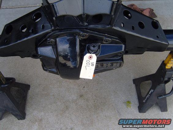 black rear axle assembly on jack stands, tag reads 'NO OIL'