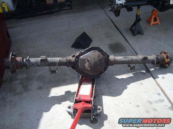 Rear axle assembly on a red hydraulic jack, with another axle assembly on jack stands in the background