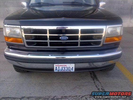 Black Ford truck front grille with chrome accents and a blue Ford logo. Washington license plate AIJ3304 is visible