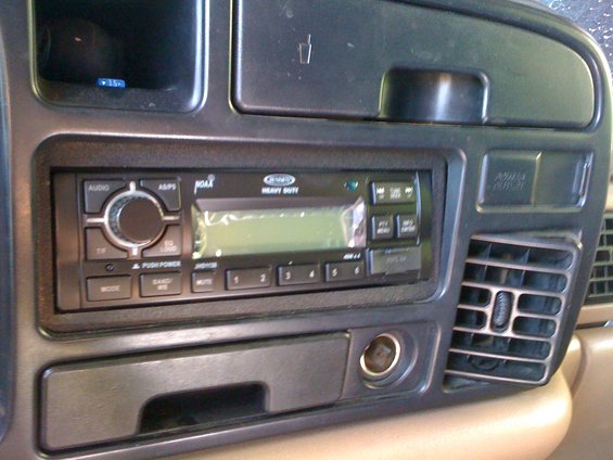Car dashboard with aftermarket stereo, air vent, and power outlet
