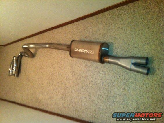 Exhaust system with a cylindrical muffler and dual tailpipes, mounted on a wall