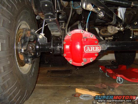 Close-up of a Jeep's rear axle, showing a red ARB differential cover and large tire