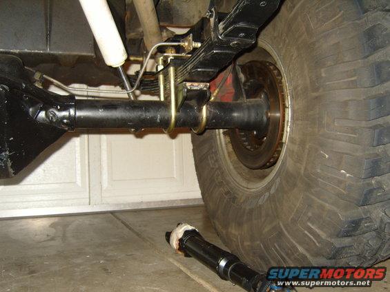 Jeep rear axle assembly with leaf springs, shock absorber, and a removed driveshaft on the floor