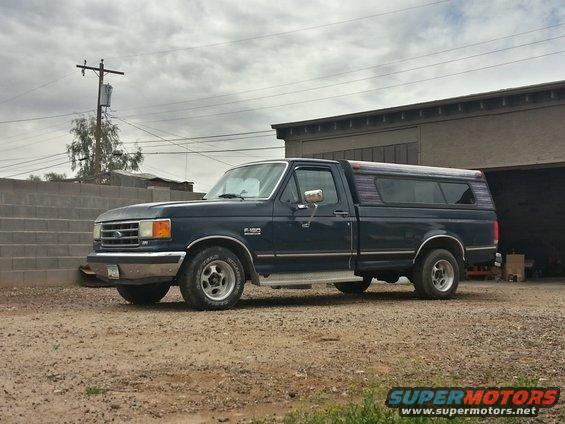 Dark blue 1989 Ford F-150 pickup truck with camper shell, side view