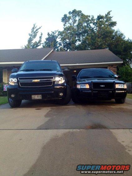 Black Ford Crown Victoria and a black Chevrolet Tahoe parked in front of a house