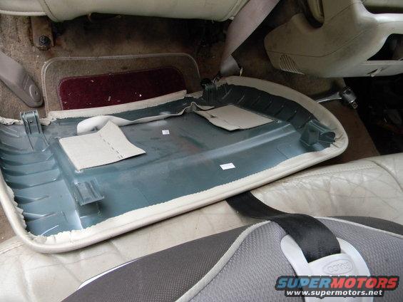 Car interior with door panel removed, showing exposed trim and seatbelt