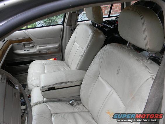 Interior of a car showing light-colored leather front seats and door panel. A Lincoln logo is visible on the seat