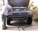 1991 Ford Bronco - A person works on the engine of a truck, with the front bumper and grille visible.