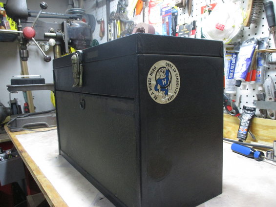 Black metal toolbox with a circular sticker that says 'BE A HENZE HERO KEEP ACCIDENTS AT ZERO'