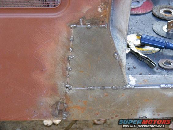 Welding patch on rusty vehicle body panel with grinder discs in background