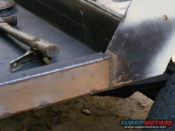 Hammer resting on a metal clamp next to a freshly welded frame section