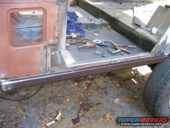 rusted vehicle body panel with tools and clamps scattered on the floor