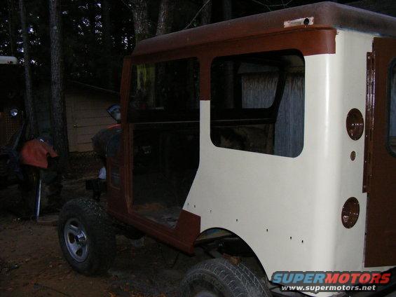Old SUV body, looks like a Toyota Land Cruiser FJ40, in brown and cream, sitting outside
