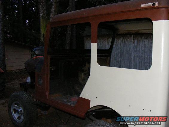 SUV body in red and white, missing doors and windows, with visible rust and repair work
