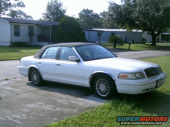 1998 Ford Crown Victoria sedan parked on a concrete driveway in front of a house