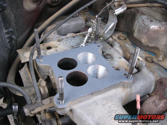 Carburetor gasket being installed on engine manifold