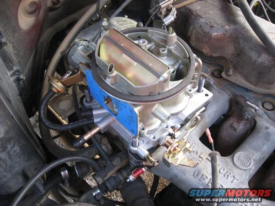 Close-up of a Holley carburetor mounted on an engine intake manifold with various hoses and wires connected