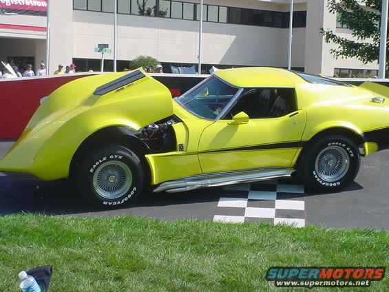 Yellow 1975 Chevrolet Corvette with hood open, showing engine details and side exhaust pipes