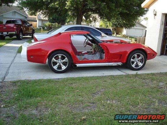 red sports car with doors removed, engine exposed, parked next to a silver car and a red pickup truck
