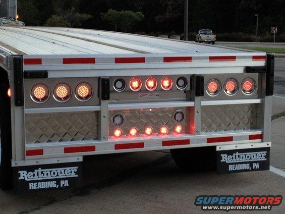 Rear view of a trailer with multiple red and amber LED lights and Reitnouer mud flaps