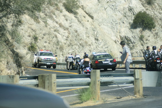 Highway Patrol car and tow truck on a roadside with several people and motorcycles