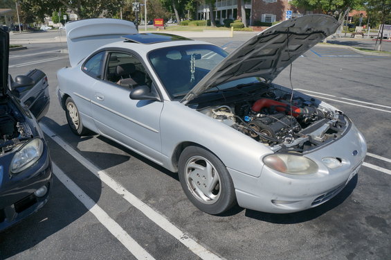 Silver Ford Escort with hood open, parked next to a dark car with hood open