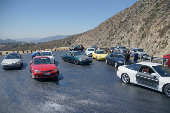 Cars parked on a winding mountain road with a hillside in the background