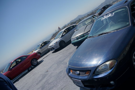 Several cars parked on a slope with a view of hills and the sky