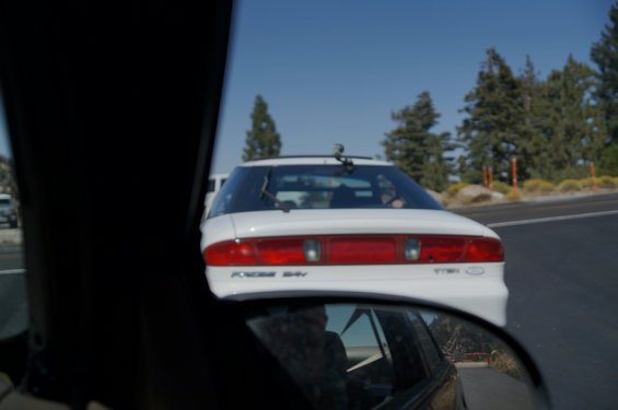 White coupe with 'Ford 24V' badge, seen from behind