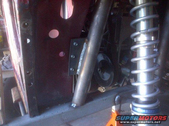 Close-up of a Jeep CJ frame with a roll cage tube and a coilover shock absorber. Modifications are visible