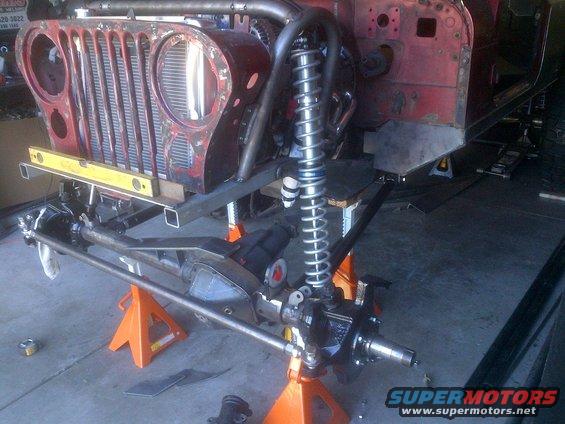 Jeep CJ front end on jack stands, showing grille, suspension, and roll cage fabrication