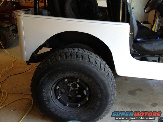 White Jeep TJ rear fender and large off-road tire. Interior seats visible