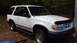 1984 Ford Bronco - This white Ford Explorer is parked outdoors with fallen leaves scattered across its hood and windshield.