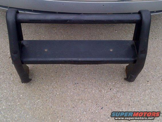 Black bull bar with two horizontal bars and a flat step, mounted on concrete