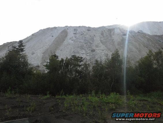 Sand pile and trees with sun flare