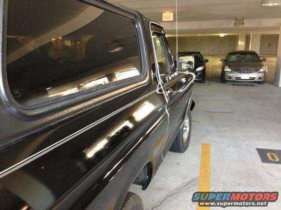 1978 Ford Bronco parked in a garage, side view. Two other cars are visible behind it