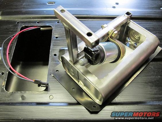 Close-up of a fuel pump assembly with red and black wires connected, mounted on a metal plate