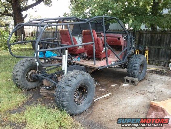 custom off-road buggy with roll cage and large tires, red seats visible inside