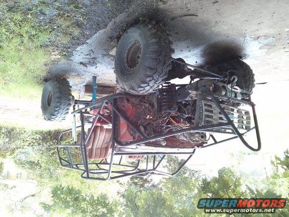 Custom buggy with roll cage, large tires, and exposed engine, sitting on dirt