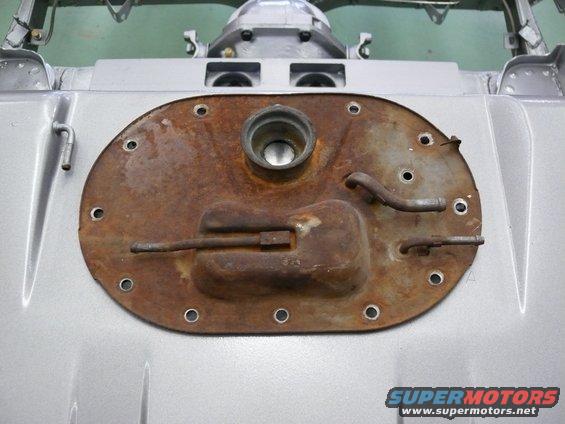 Rusty oval fuel tank sending unit cover with fuel lines attached
