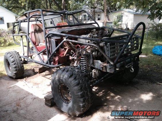 Custom buggy with roll cage, large tires, and exposed engine, sitting on blocks