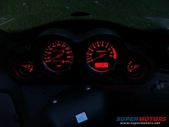 Red illuminated dashboard gauges with mph and rpm dials, and a digital display showing 737