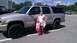 2005 Chevrolet Suburban - A woman and child pose in front of a silver SUV in a parking lot.