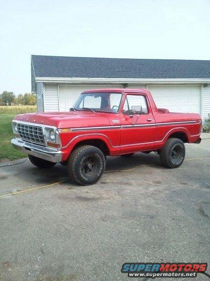 Red 1978 Ford Bronco parked in front of a garage