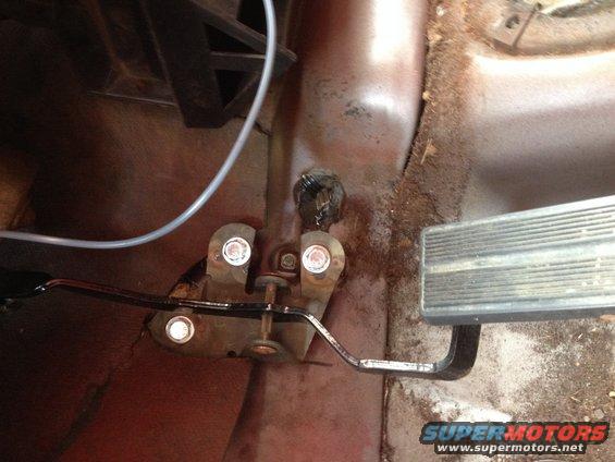 Close-up of brake and accelerator pedals on a vehicle's floor. Metal pedals show wear