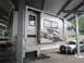 2008 Ford F-450 - A truck camper is parked next to a sedan under a covered structure, with a boat on a trailer visible in the background.