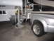 2008 Ford F-450 - A silver truck with a camper body is parked indoors, showing its dually rear wheels and extended folding stairs.