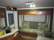 2008 Ford F-450 - The interior of a recreational vehicle features a sofa, kitchen counter with sink, and overhead storage cabinets.